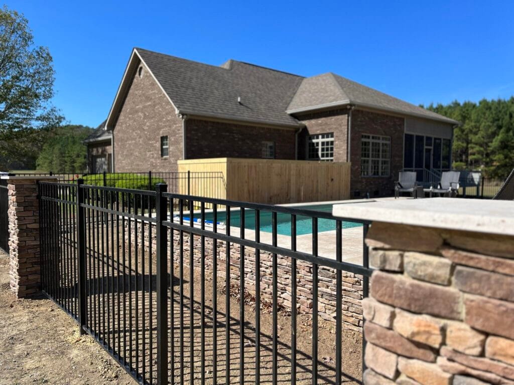 Backyard pool area with black aluminum fence and wood privacy fence installed for style, safety, and outdoor privacy in Shelby County