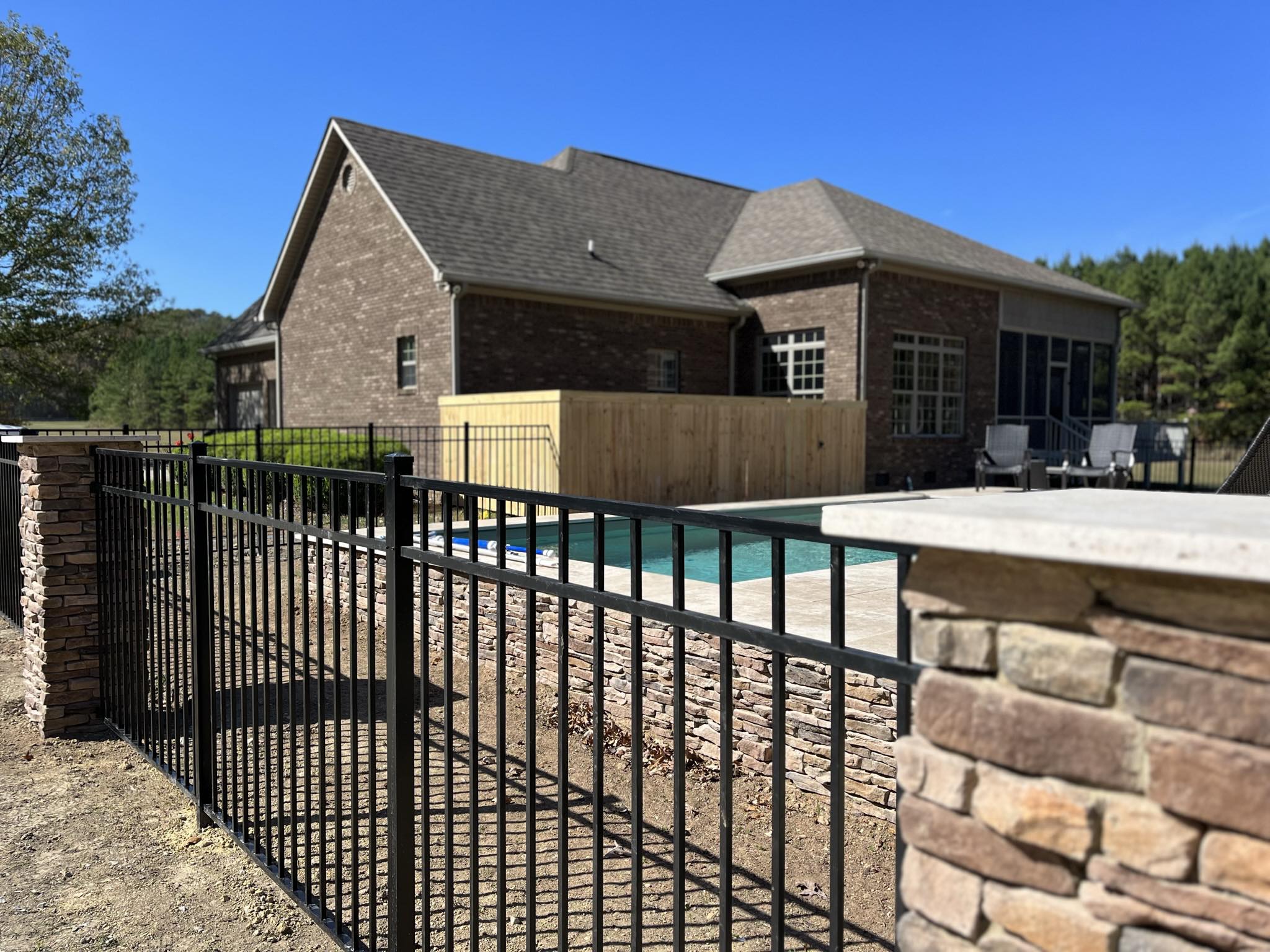 Backyard pool area with black aluminum fence and wood privacy fence installed for style, safety, and outdoor privacy in Shelby County