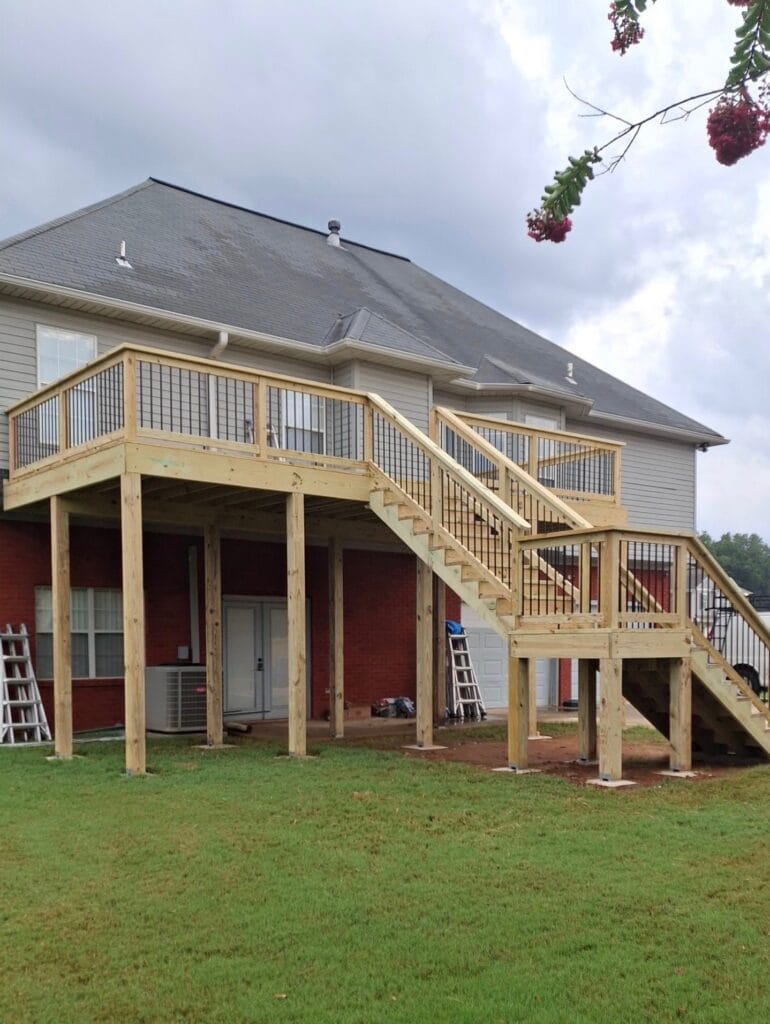 Elevated custom deck construction project and staircase installation in Bessemer, Alabama with modern railing, enhancing outdoor living space and home aesthetics