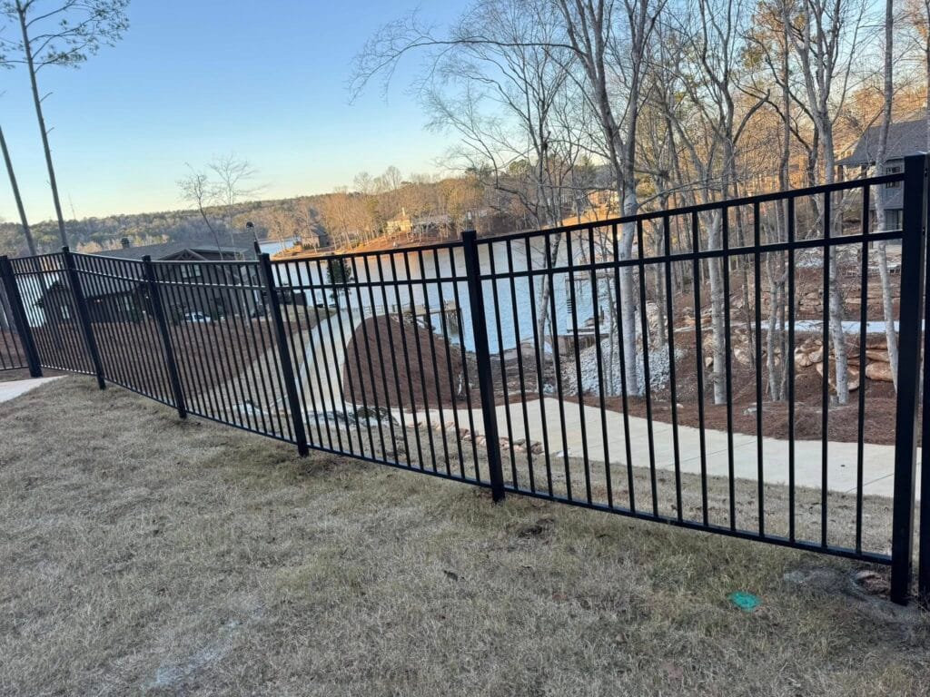 Black aluminum pool fence and 3‑rail pressure‑treated wood fence with copper post caps installed at a Lake Martin area property in Helena, AL.